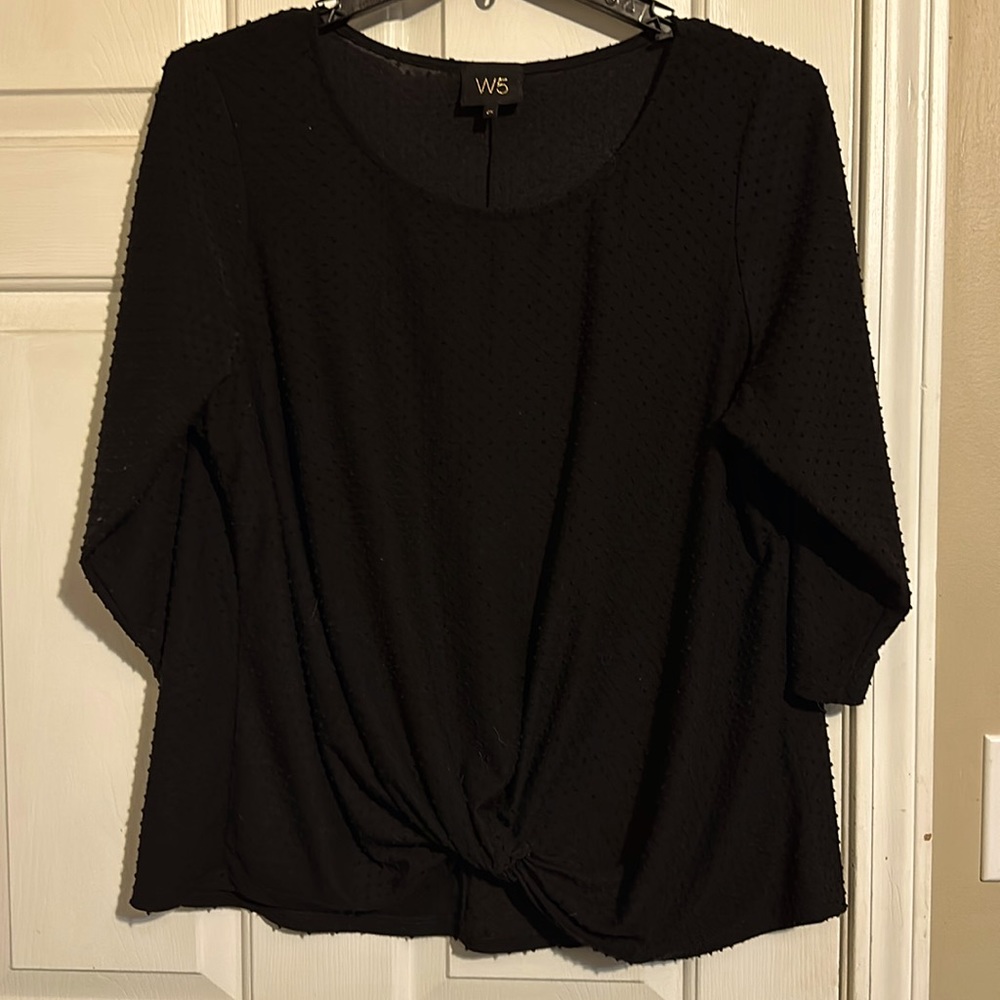 Black top with raised polka dots and twist detail at the front hem